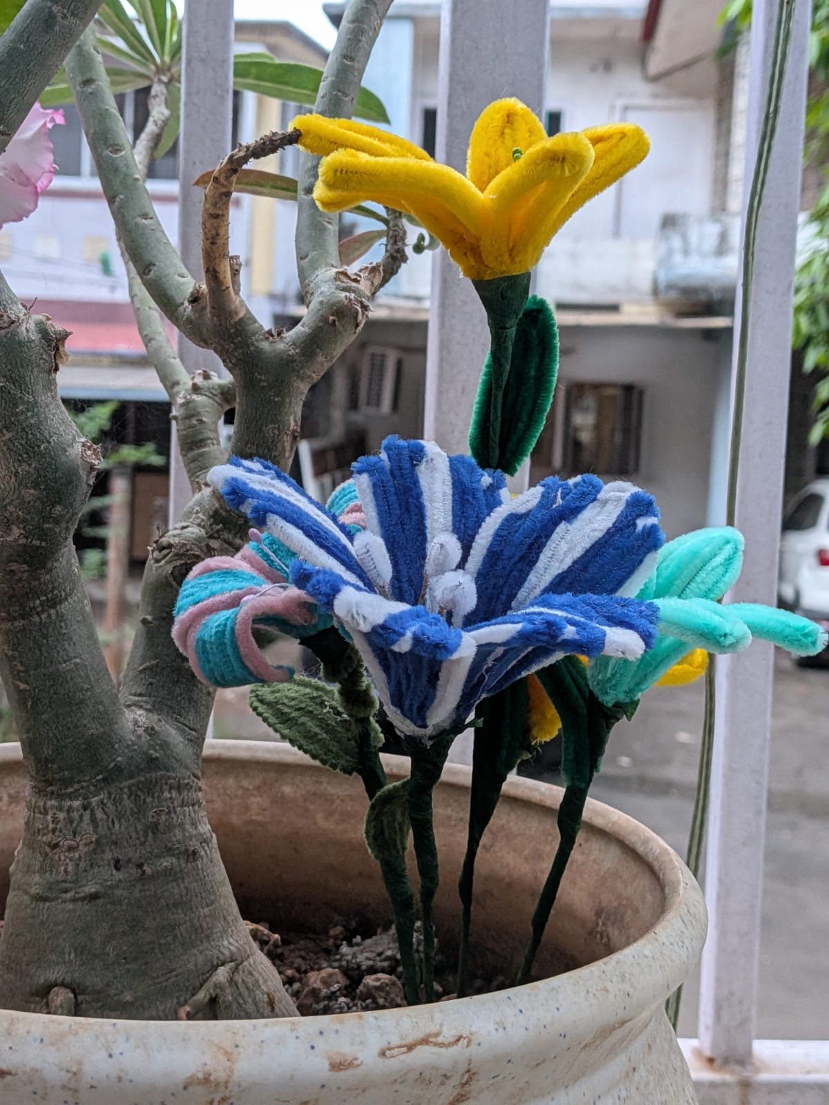 Blue and yellow crochet flowers in a garden setting